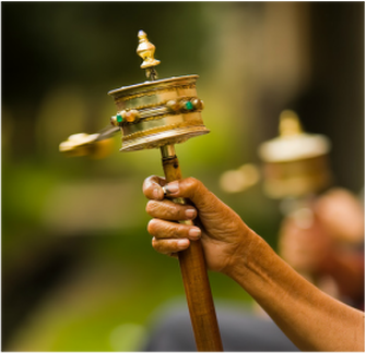 A Tibetan prayer wheel which has a rotating disc on a graspable stick. 